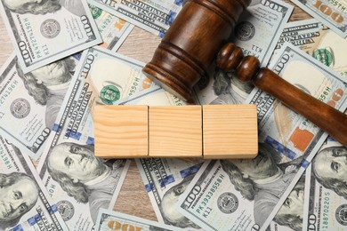 Photo of Tax law. Blank wooden cubes, dollar banknotes and gavel on table, top view