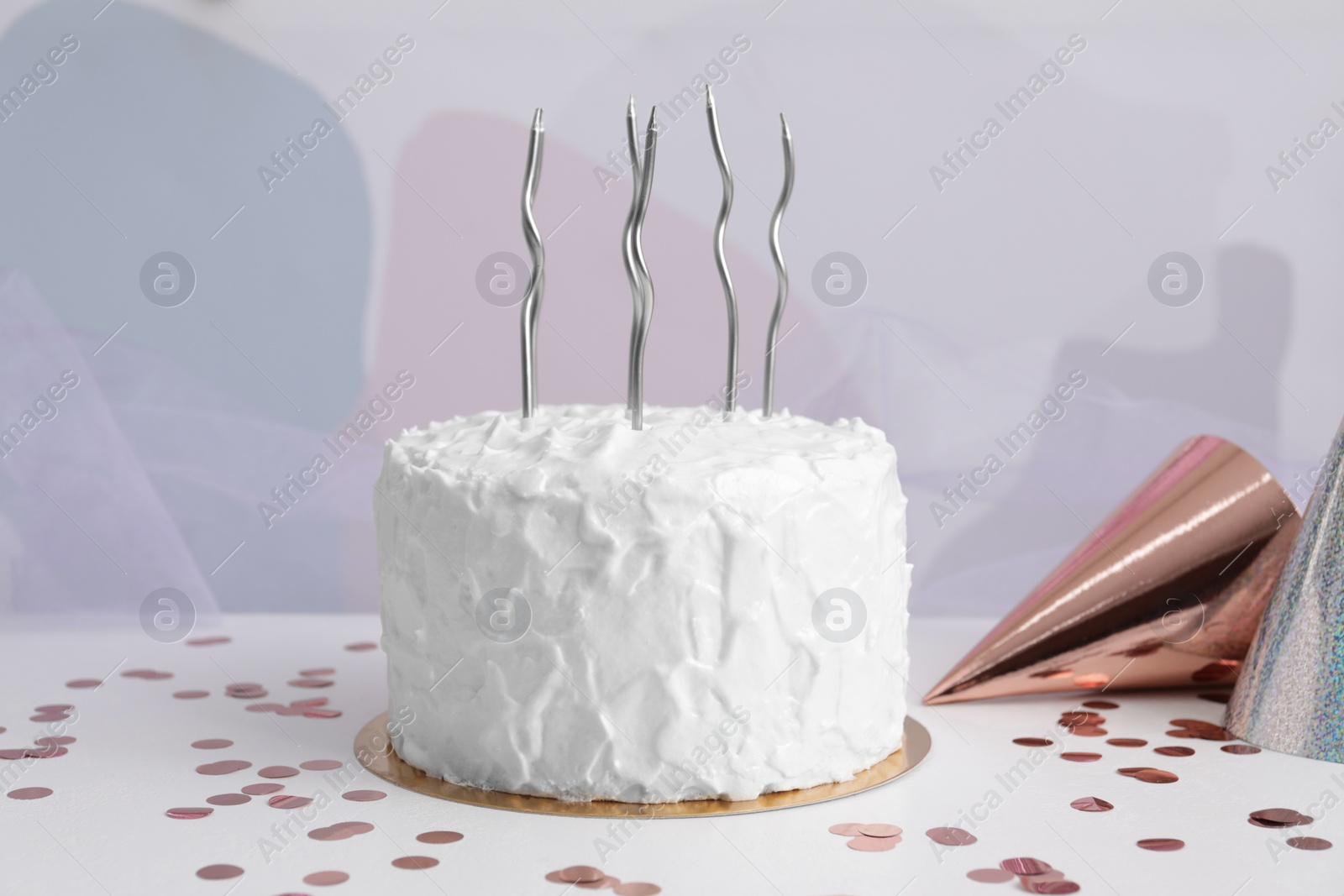 Photo of Delicious cake with candles and party hats on white table