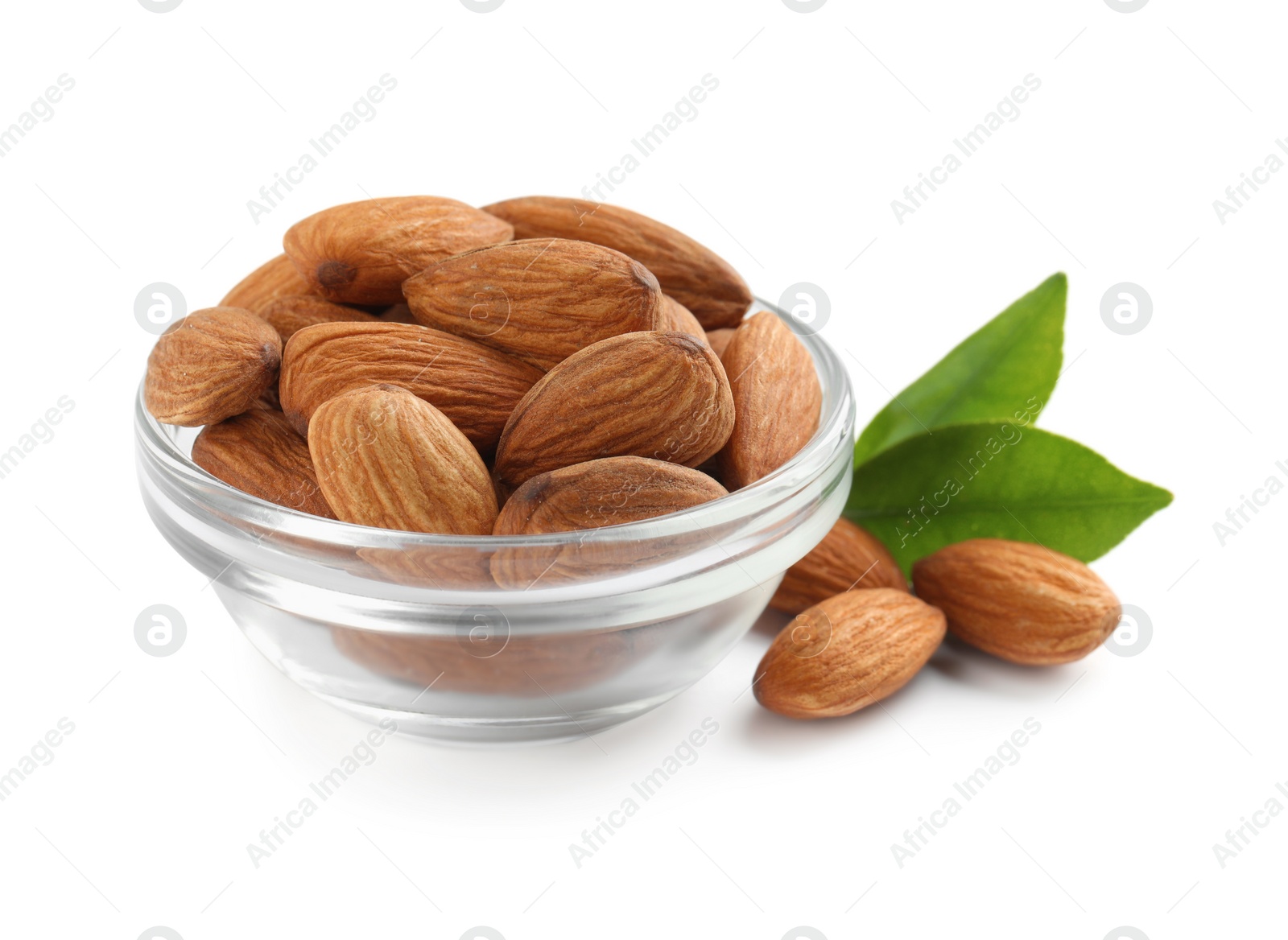 Photo of Glass bowl with organic almond nuts and green leaves on white background. Healthy snack