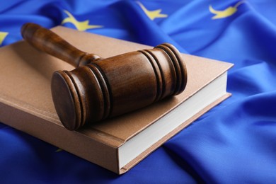 Wooden judge's gavel and book on flag of European Union, closeup