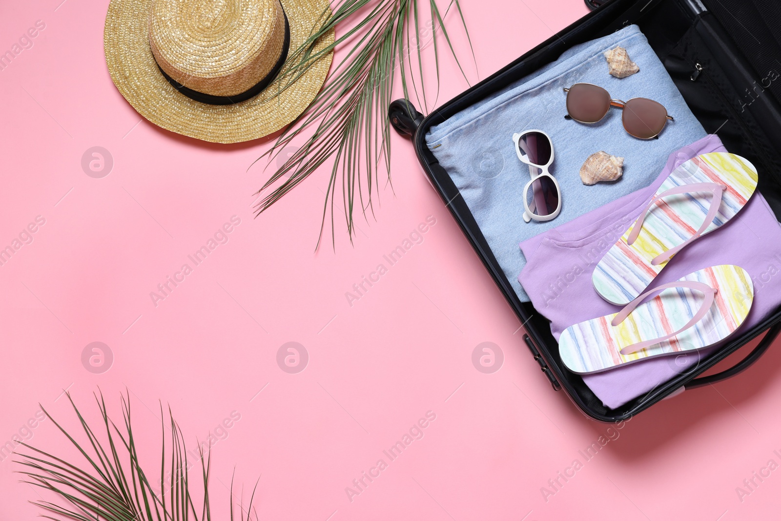 Photo of Suitcase with beach accessories on pink background, flat lay. Space for text
