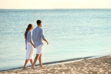 Happy young couple walking together on beach