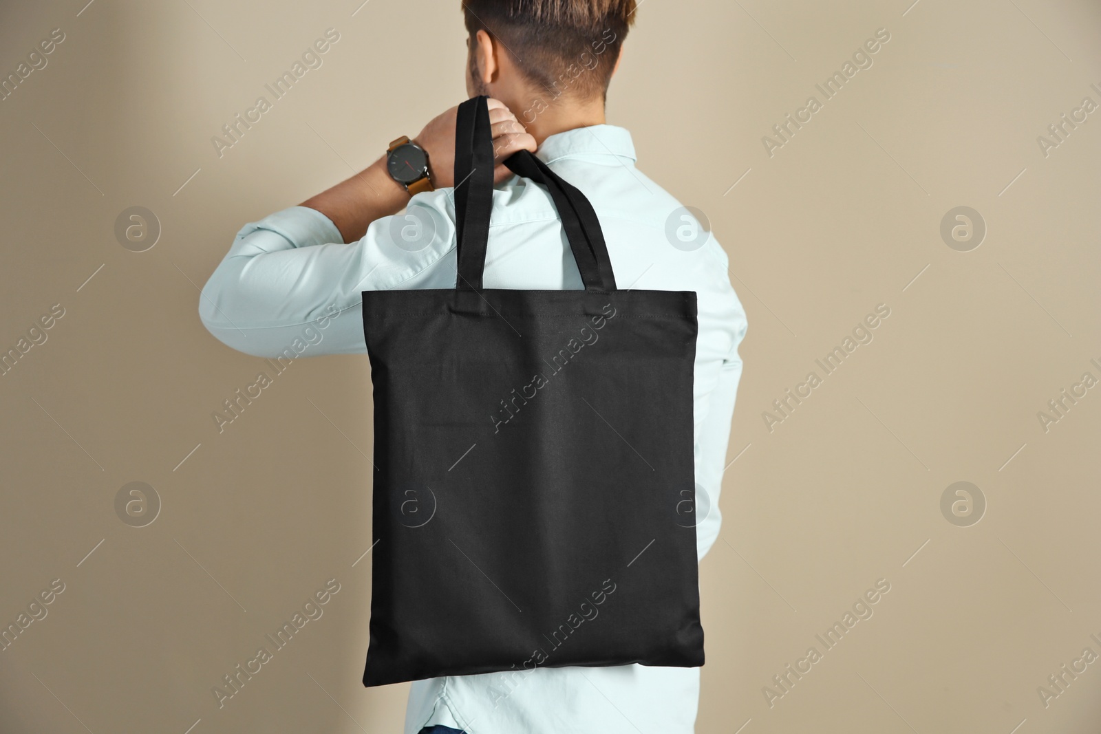 Photo of Young man holding textile bag on color background, closeup. Mockup for design