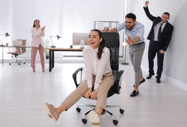 Photo of Office employee giving his colleague ride in chair at workplace. Space for text