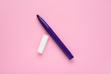 Photo of Bright purple marker and cap on light pink background, flat lay