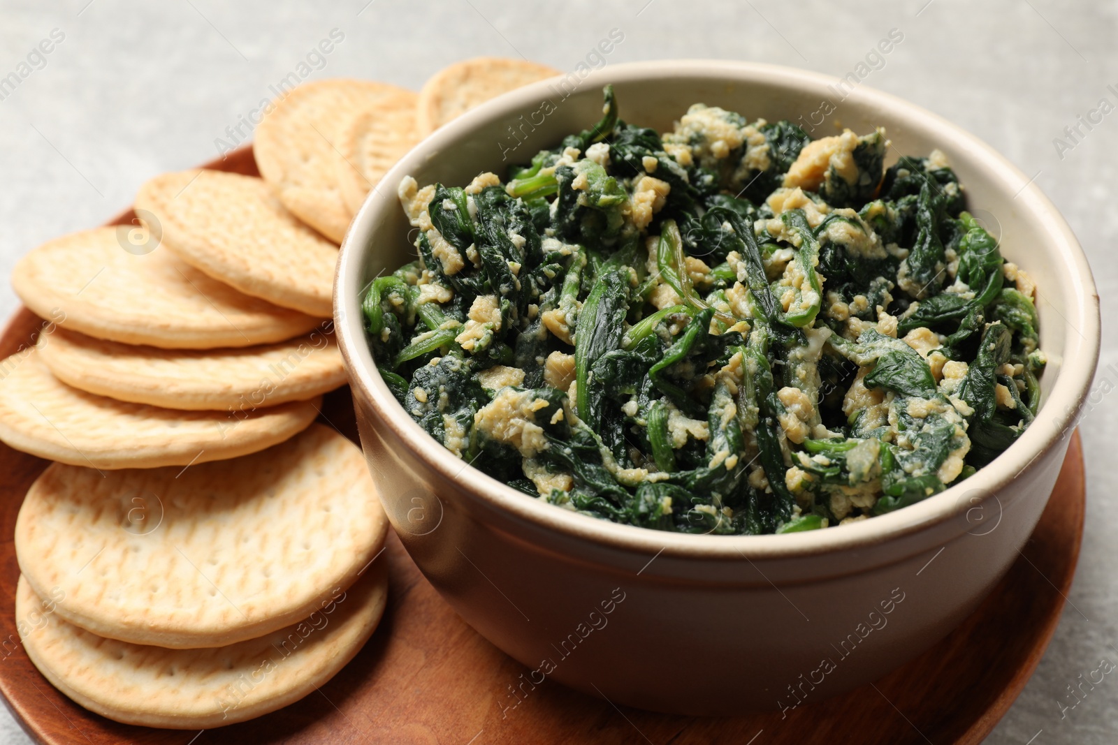 Photo of Tasty spinach dip with egg and crackers on grey table, closeup