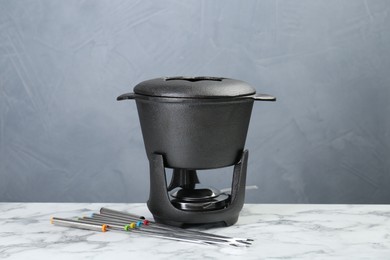 Photo of Fondue set on white marble table against light grey background