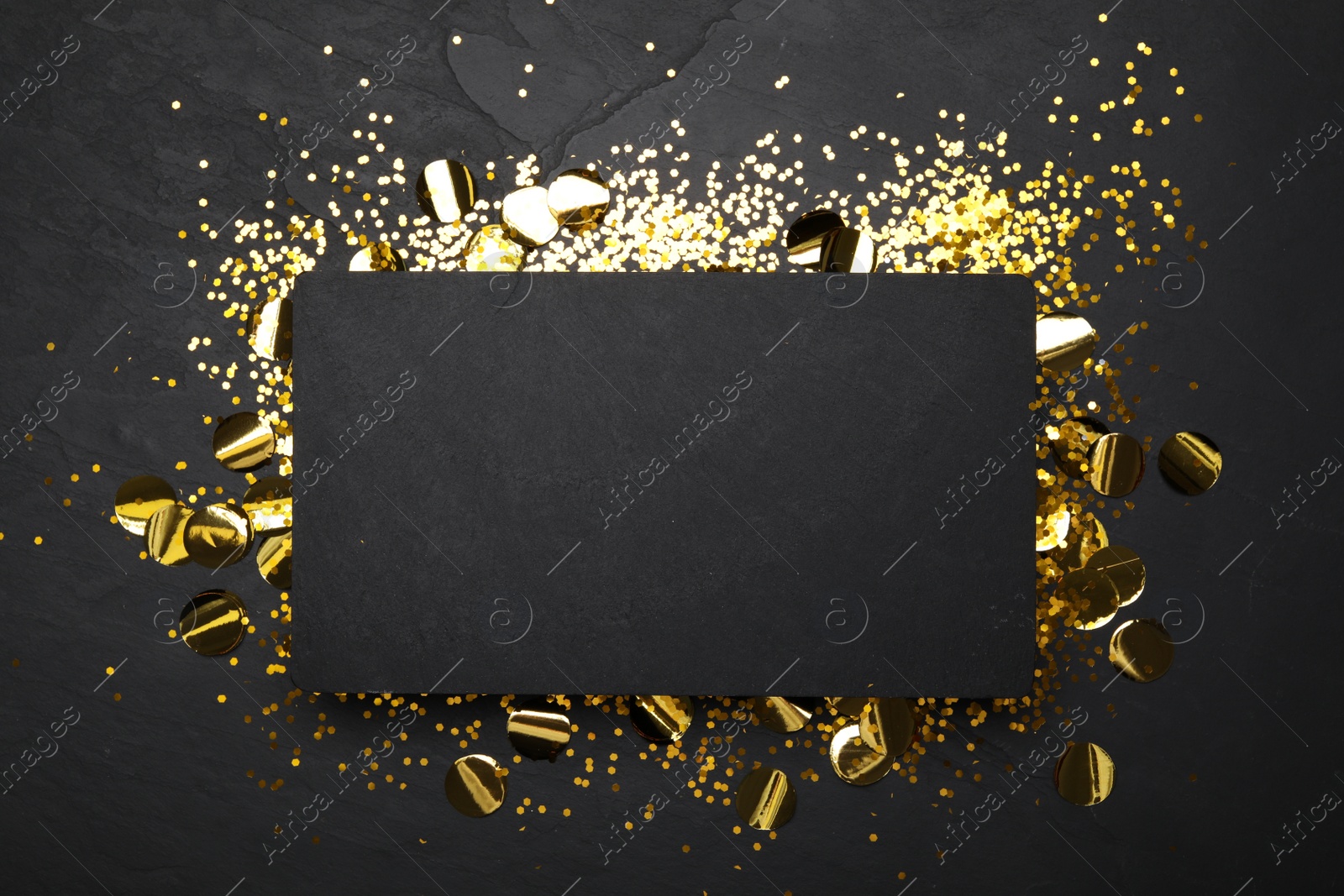 Photo of Slate board and confetti on black background, top view. Space for text