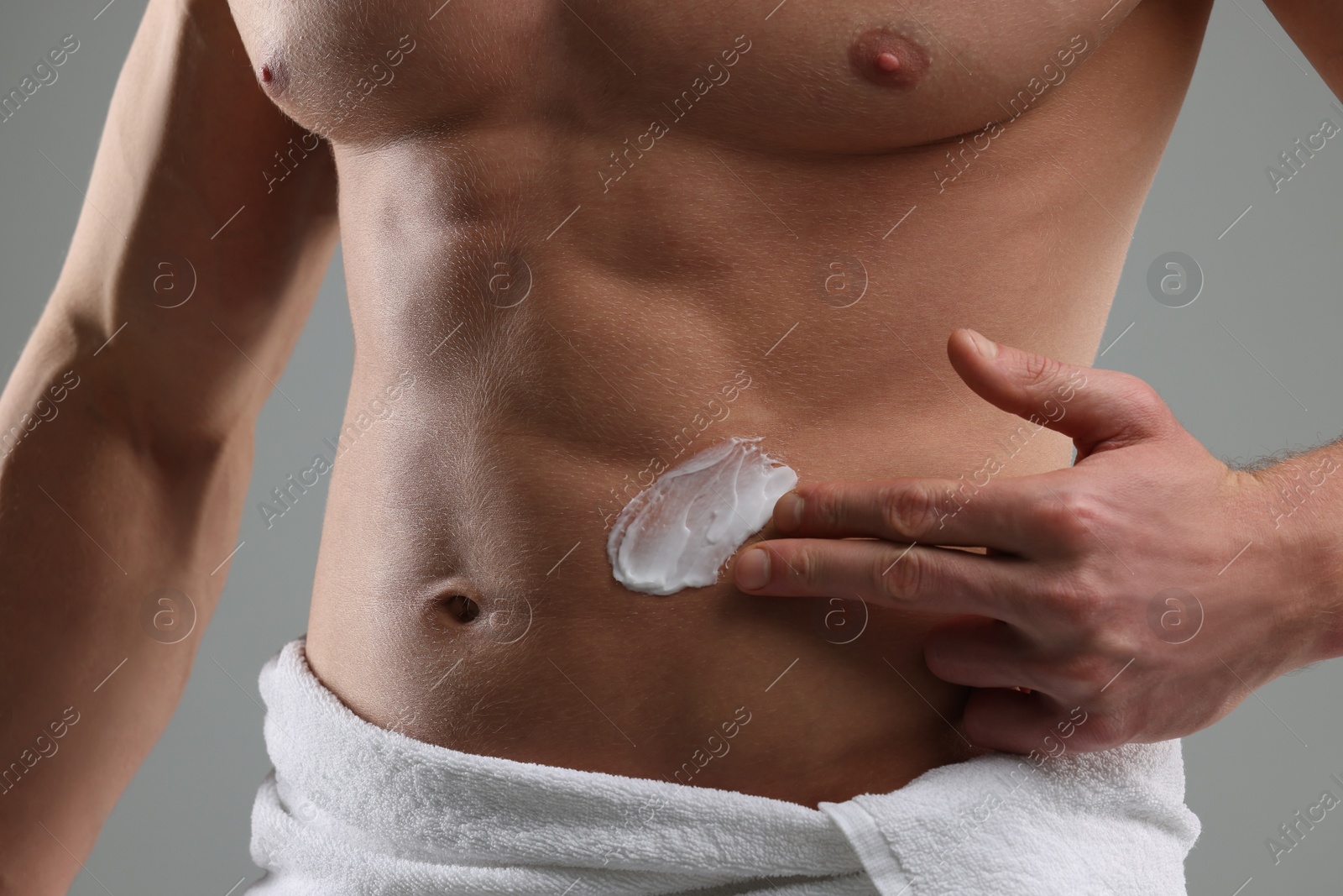 Photo of Man applying moisturizing cream onto his body on grey background, closeup