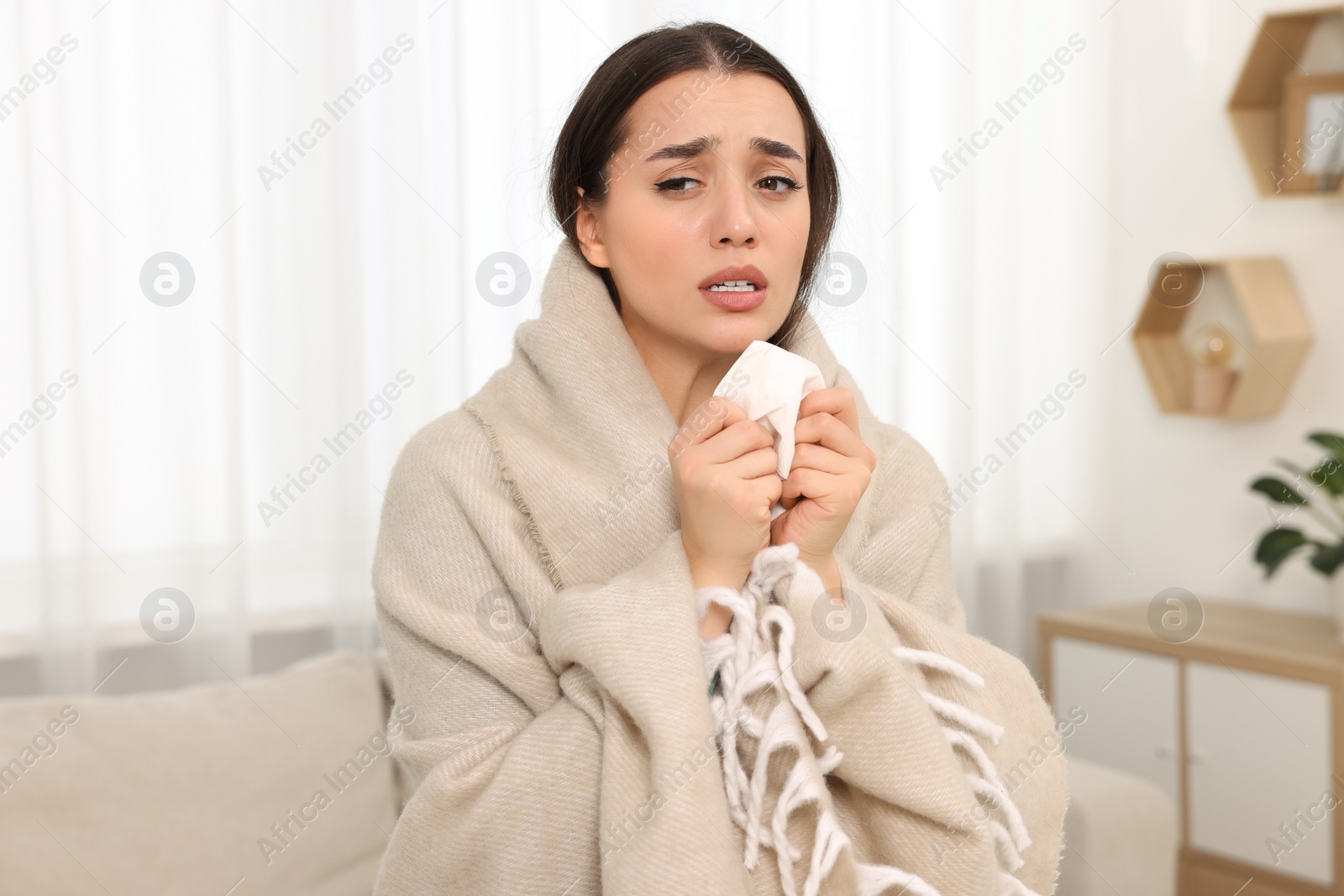 Photo of Sick woman wrapped in blanket with tissue at home. Cold symptoms