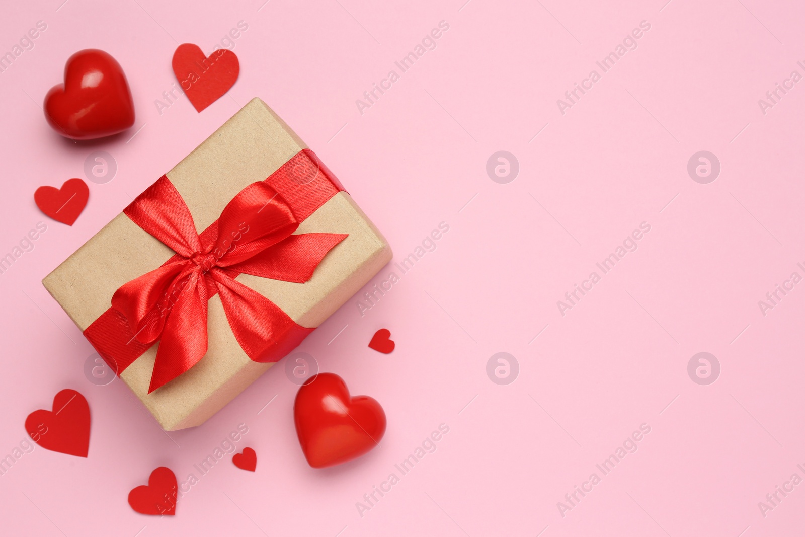 Photo of Beautiful gift box and red decorative hearts on pink background, flat lay. Space for text