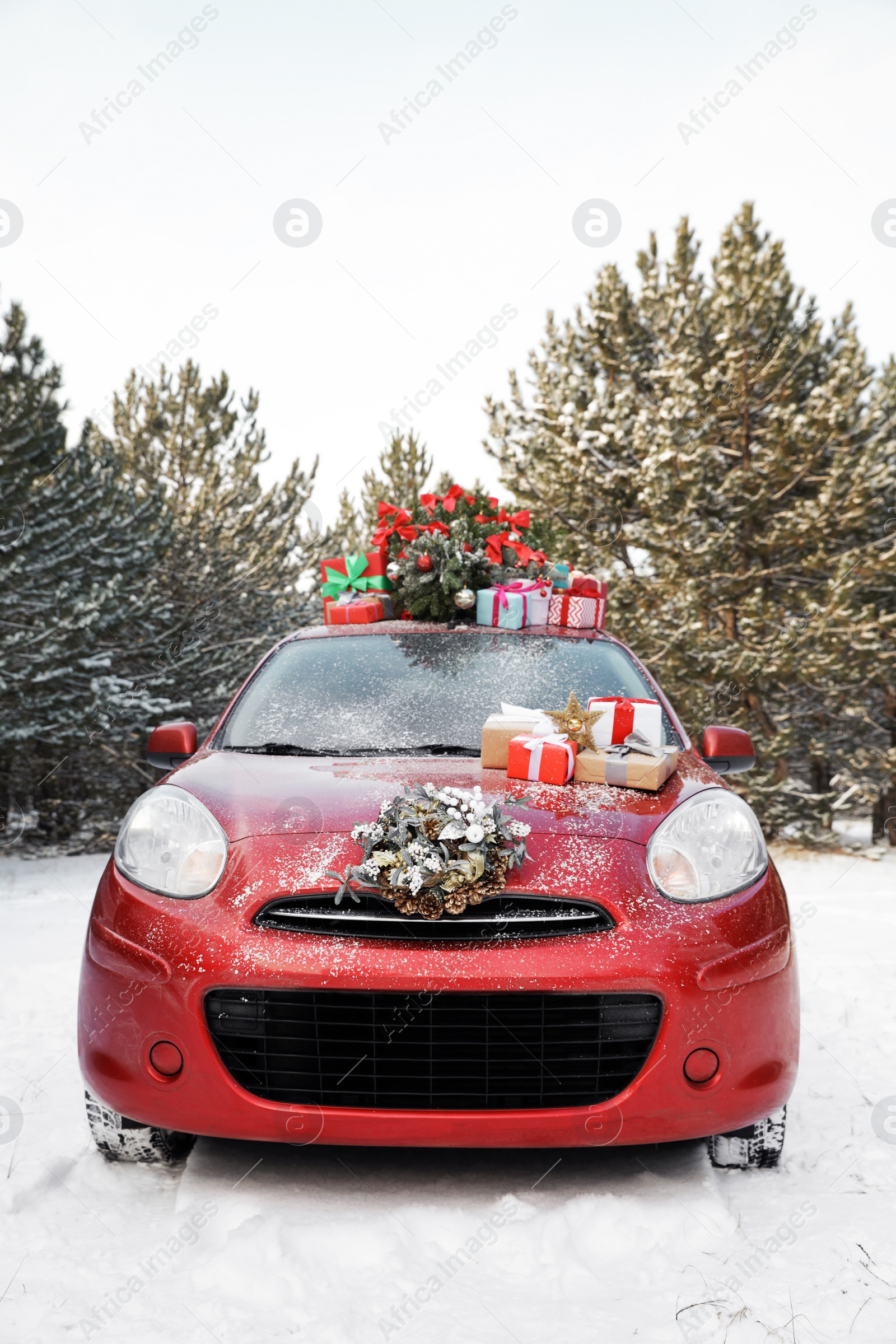 Photo of Car with Christmas tree, wreath and gifts in snowy forest on winter day