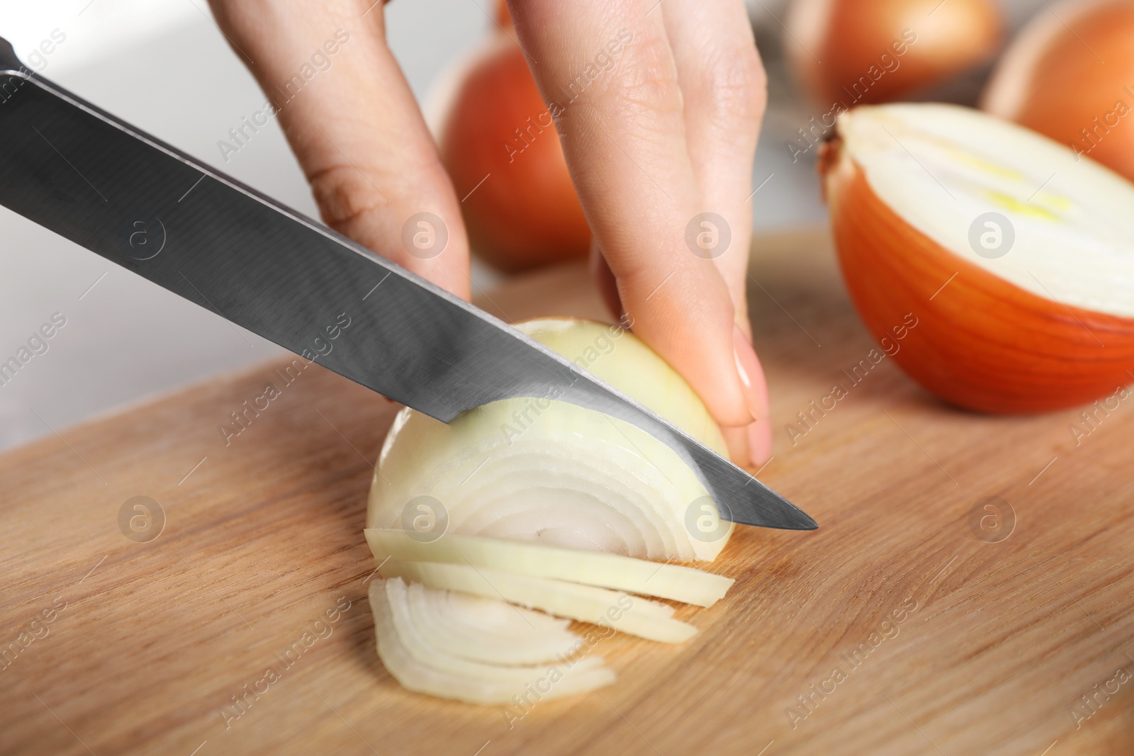 Photo of Woman cutting ripe onion at table, closeup