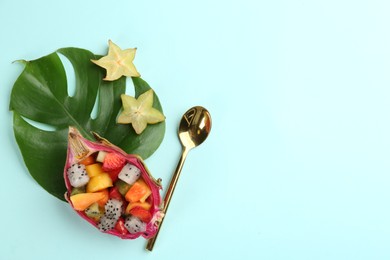 Delicious exotic fruit salad and spoon on turquoise background, flat lay. Space for text