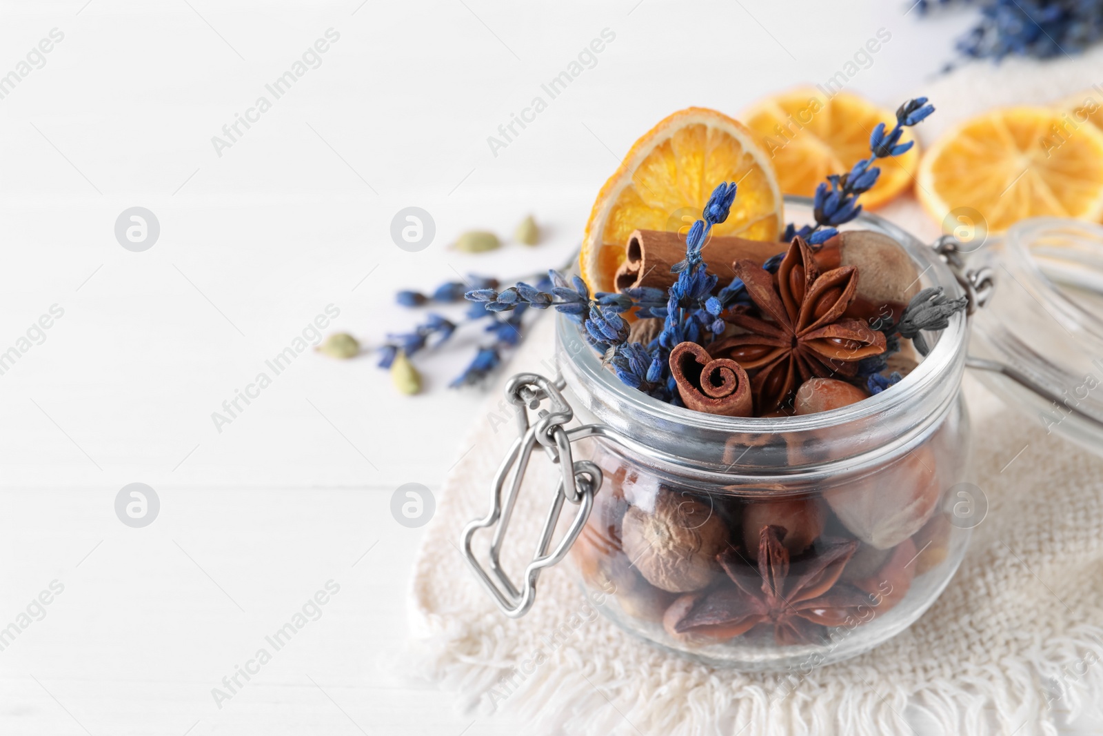 Photo of Aromatic potpourri in glass jar on white table, closeup. Space for text