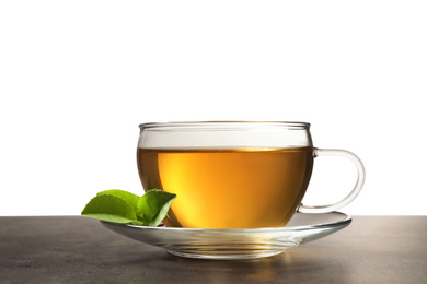 Cup of green tea and leaves on grey table