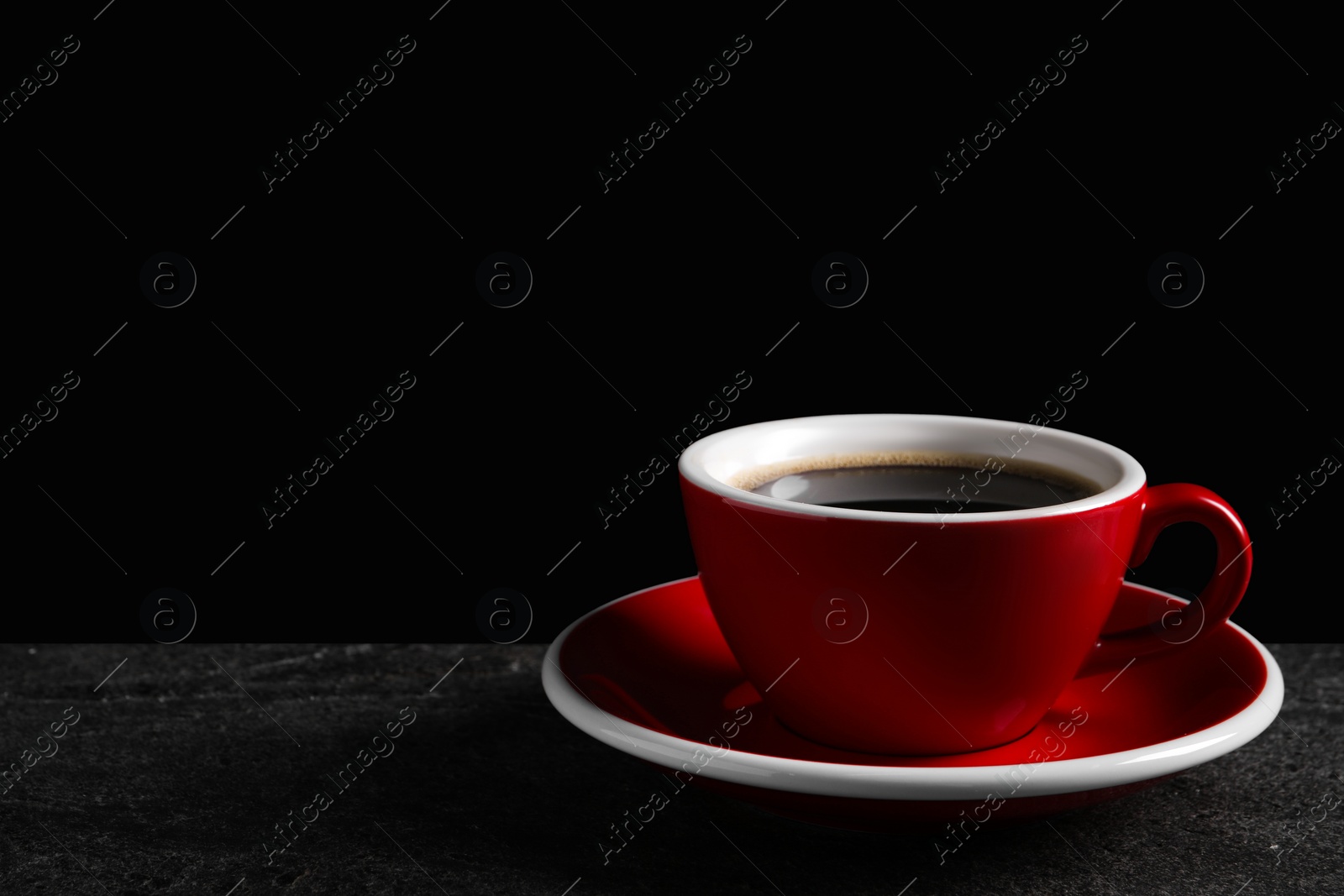 Photo of Red cup with aromatic coffee on black textured table. Space for text