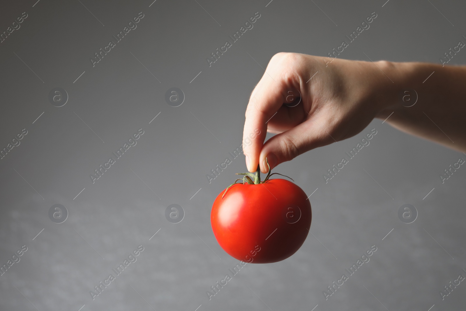 Photo of Woman with ripe tomato on grey background, closeup. Space for text