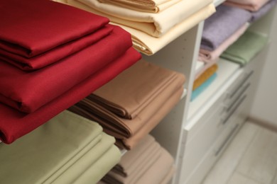 Photo of Different colorful bed linens on display in shop, closeup
