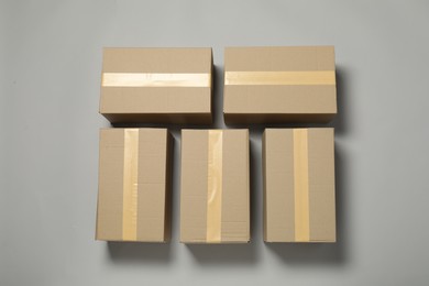 Many closed cardboard boxes with tape on light grey background, flat lay