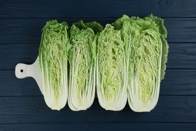 Photo of Cut fresh ripe Chinese cabbages on blue wooden table, flat lay