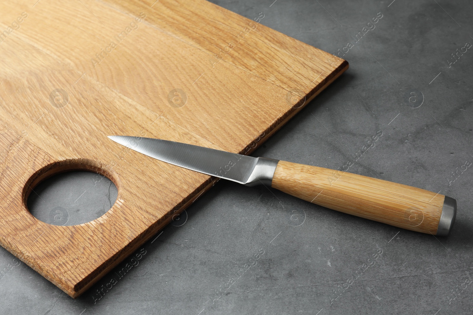 Photo of Knife and wooden board on grey textured table