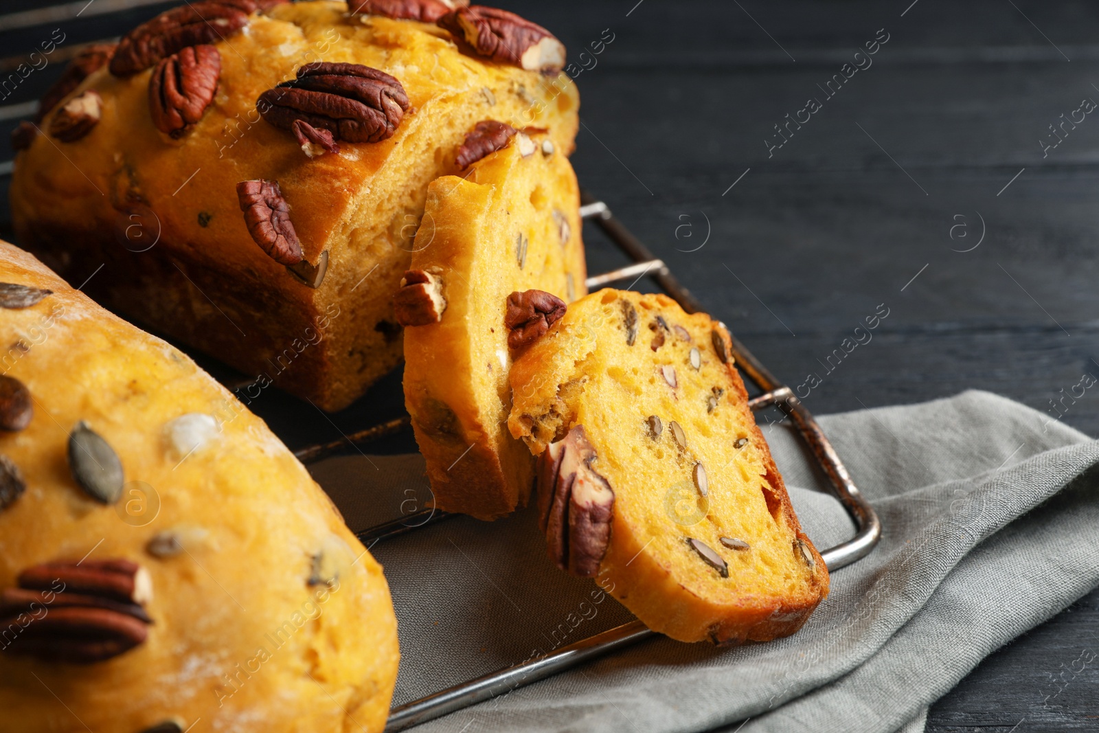 Photo of Delicious pumpkin bread with pecan nuts on black wooden table, closeup
