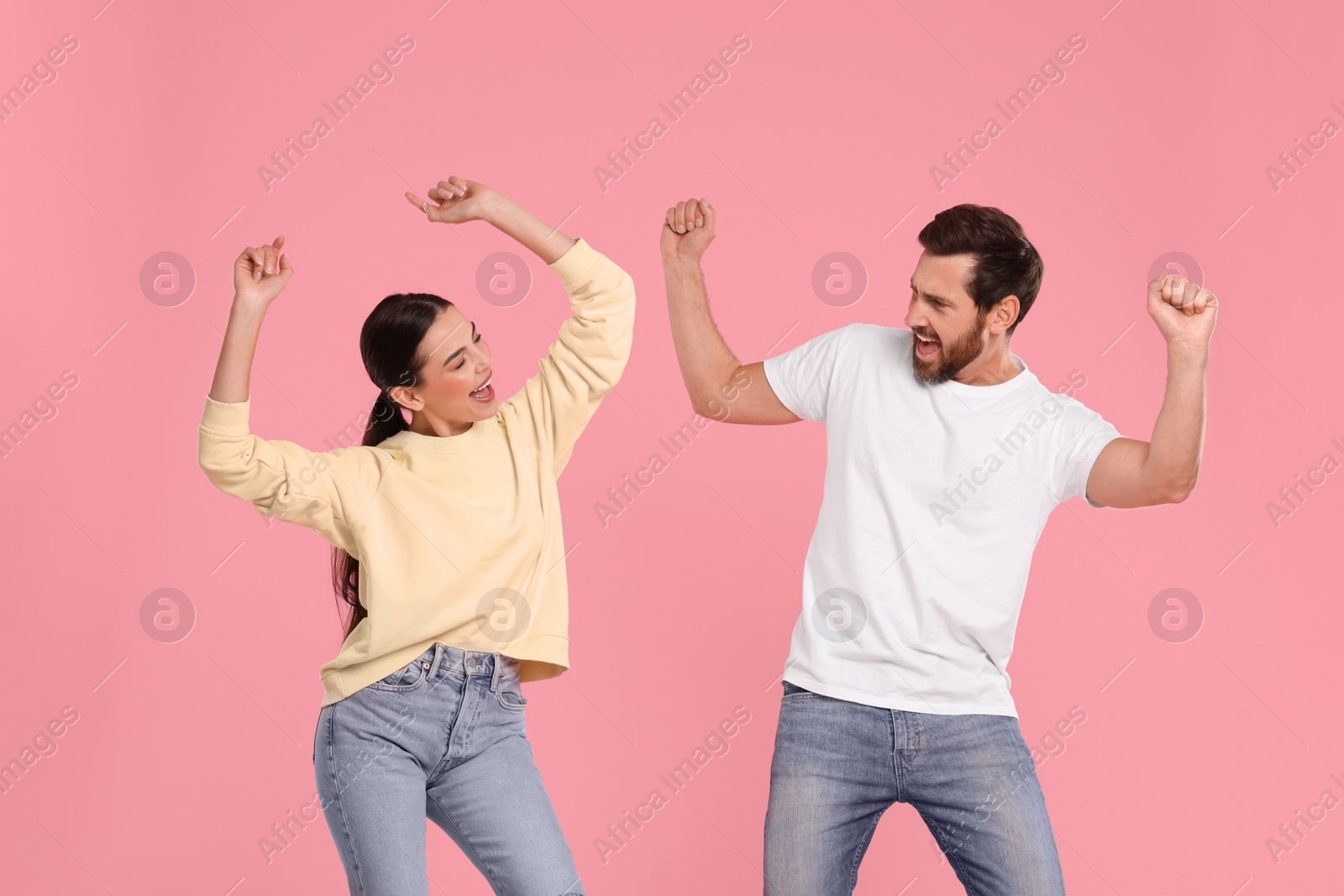 Photo of Happy couple dancing together on pink background