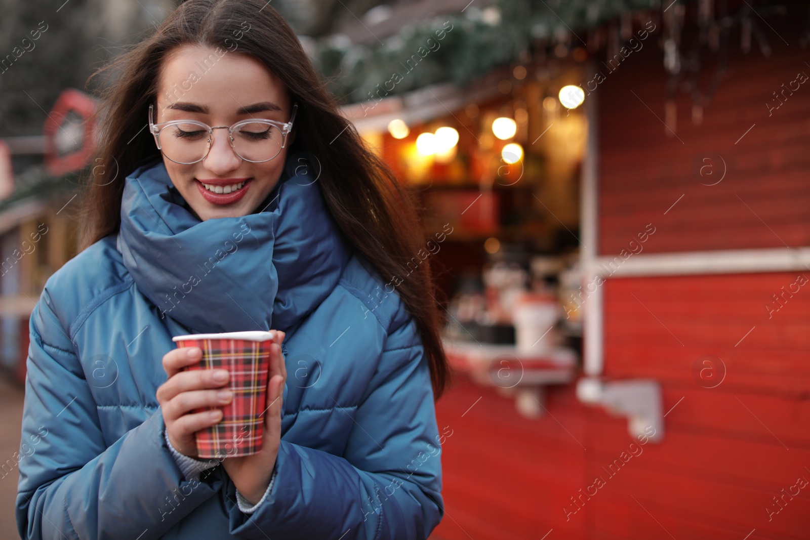 Photo of Woman with cup of mulled wine at winter fair. Space for text