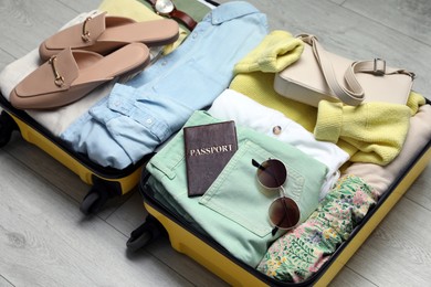 Photo of Open suitcase packed for trip on floor, closeup