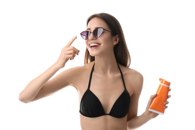 Young woman applying sun protection cream on white background