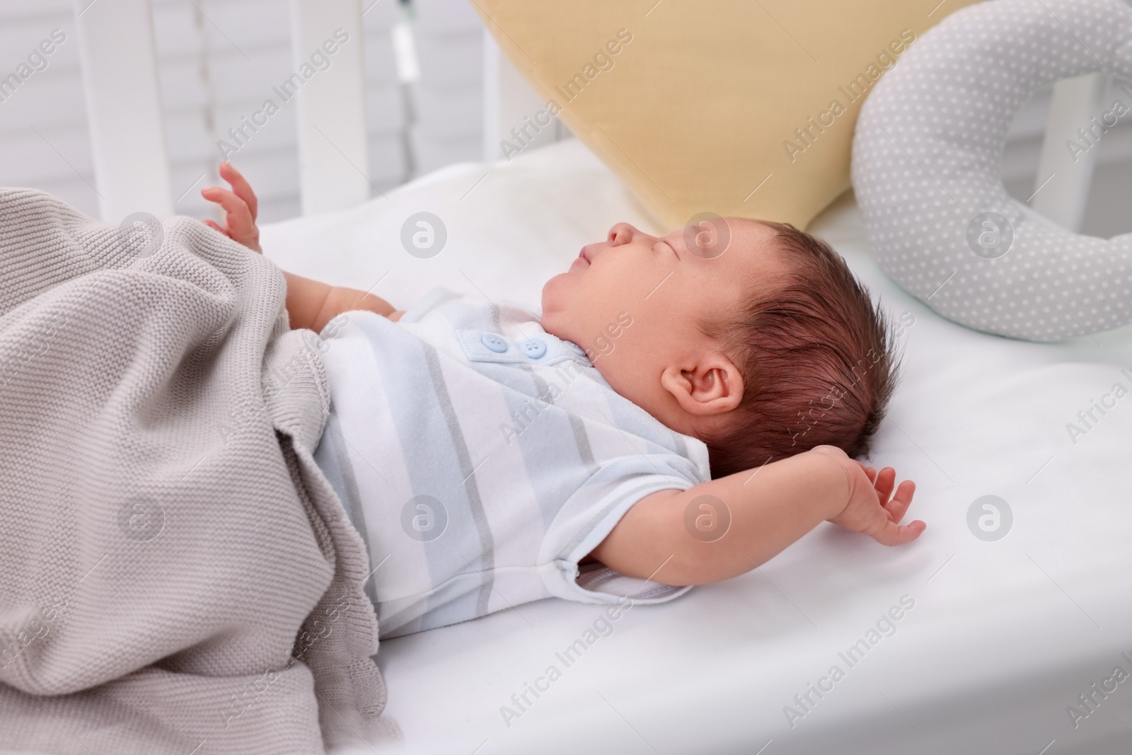 Photo of Cute newborn baby sleeping under blanket in crib at home