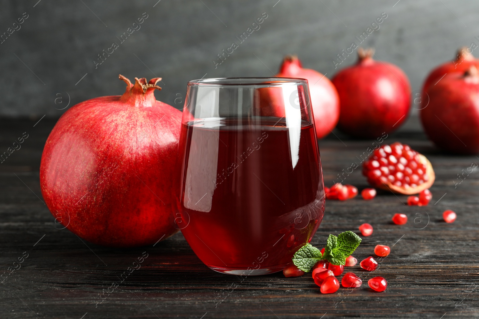 Photo of Glass of pomegranate juice and fresh fruits on table against grey background