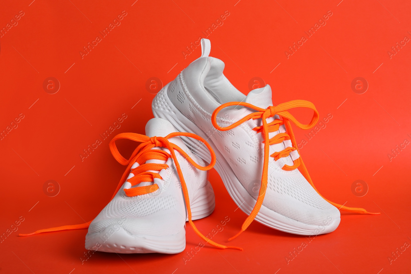 Photo of Pair of stylish shoes with orange laces on color background