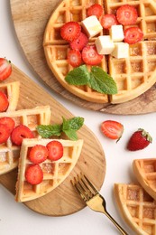 Tasty Belgian waffles with strawberries, mint and fork on white table, flat lay