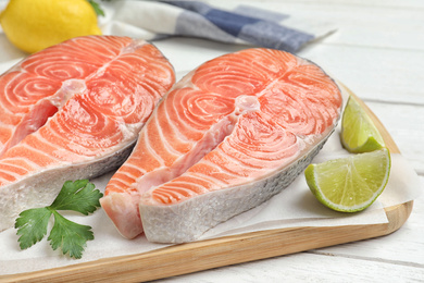 Photo of Fresh raw salmon with parsley and lime on white wooden table. Fish delicacy