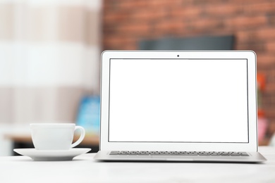 Laptop with blank screen on table indoors. Space for text