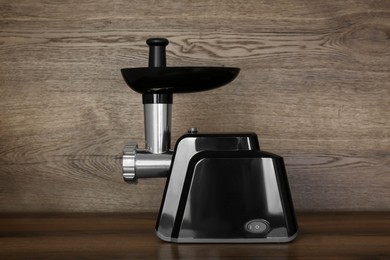 Modern electric meat grinder on wooden table