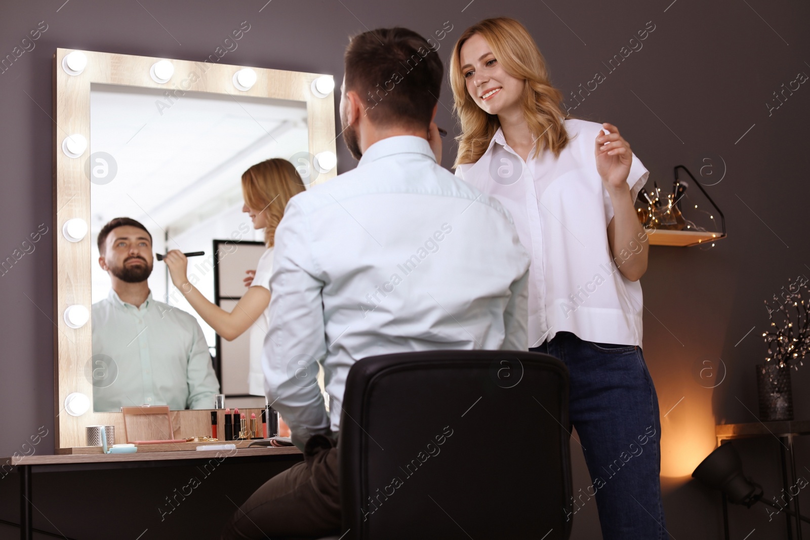 Photo of Professional makeup artist working with client in dressing room