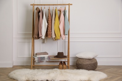 Photo of Stylish warm clothes on rack in dressing room interior