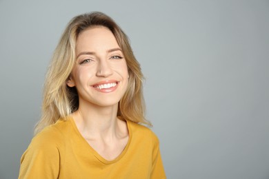 Photo of Portrait of happy young woman with beautiful blonde hair and charming smile on grey background. Space for text