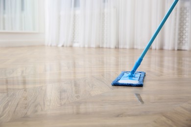Photo of Washing of parquet floor with mop indoors, closeup. Space for text