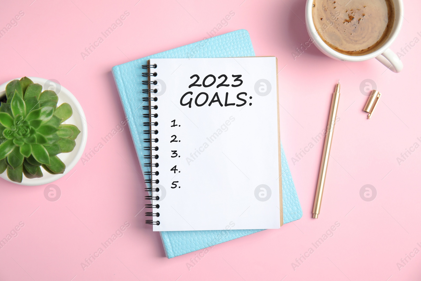 Image of Notebook with inscription 2023 Goals, cup of coffee, plant and pen on pink background, flat lay. New Year aims 