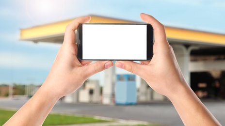 Image of Man paying for refueling via smartphone at gas station, closeup. Device with empty screen