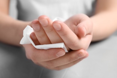 Photo of Woman wiping hands with paper towel at grey table, closeup