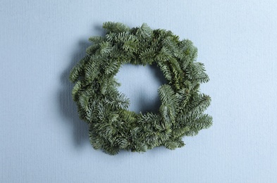 Christmas wreath made of fir tree branches on light blue background