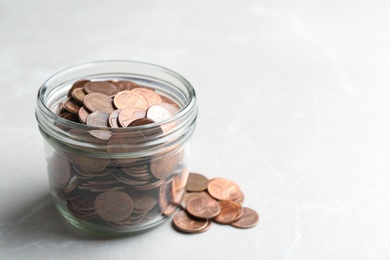 Photo of Glass jar and coins on light background. Space for text