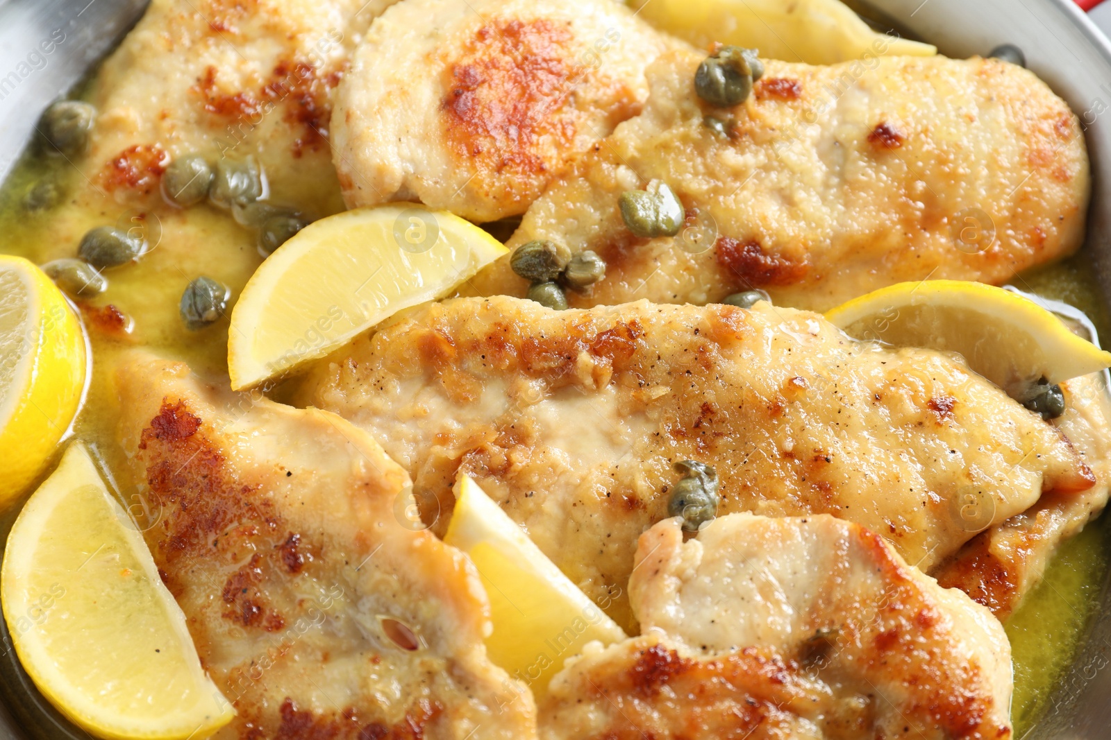 Photo of Delicious chicken piccata with lemons as background, closeup