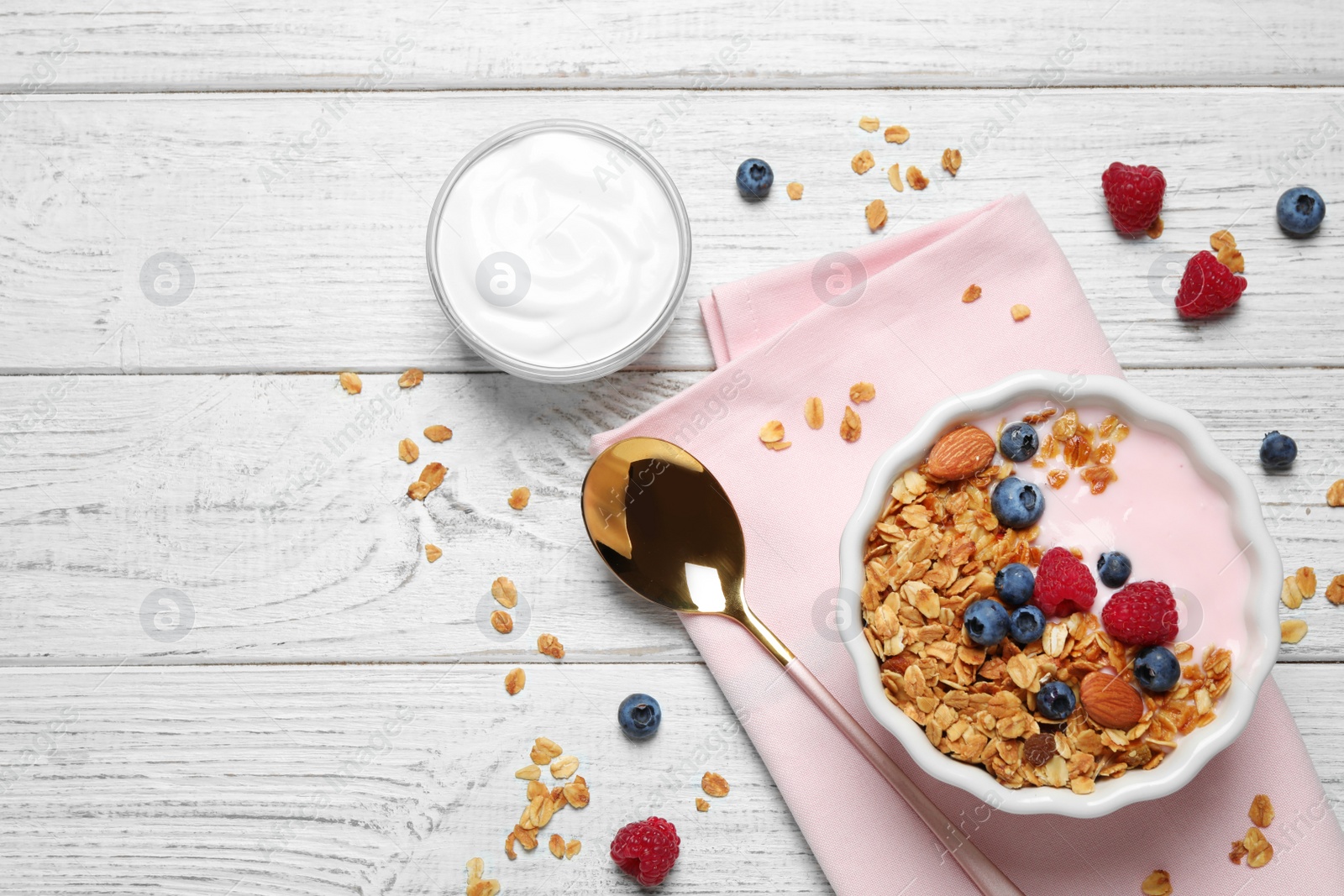 Photo of Tasty homemade granola served on white wooden table, flat lay. Healthy breakfast