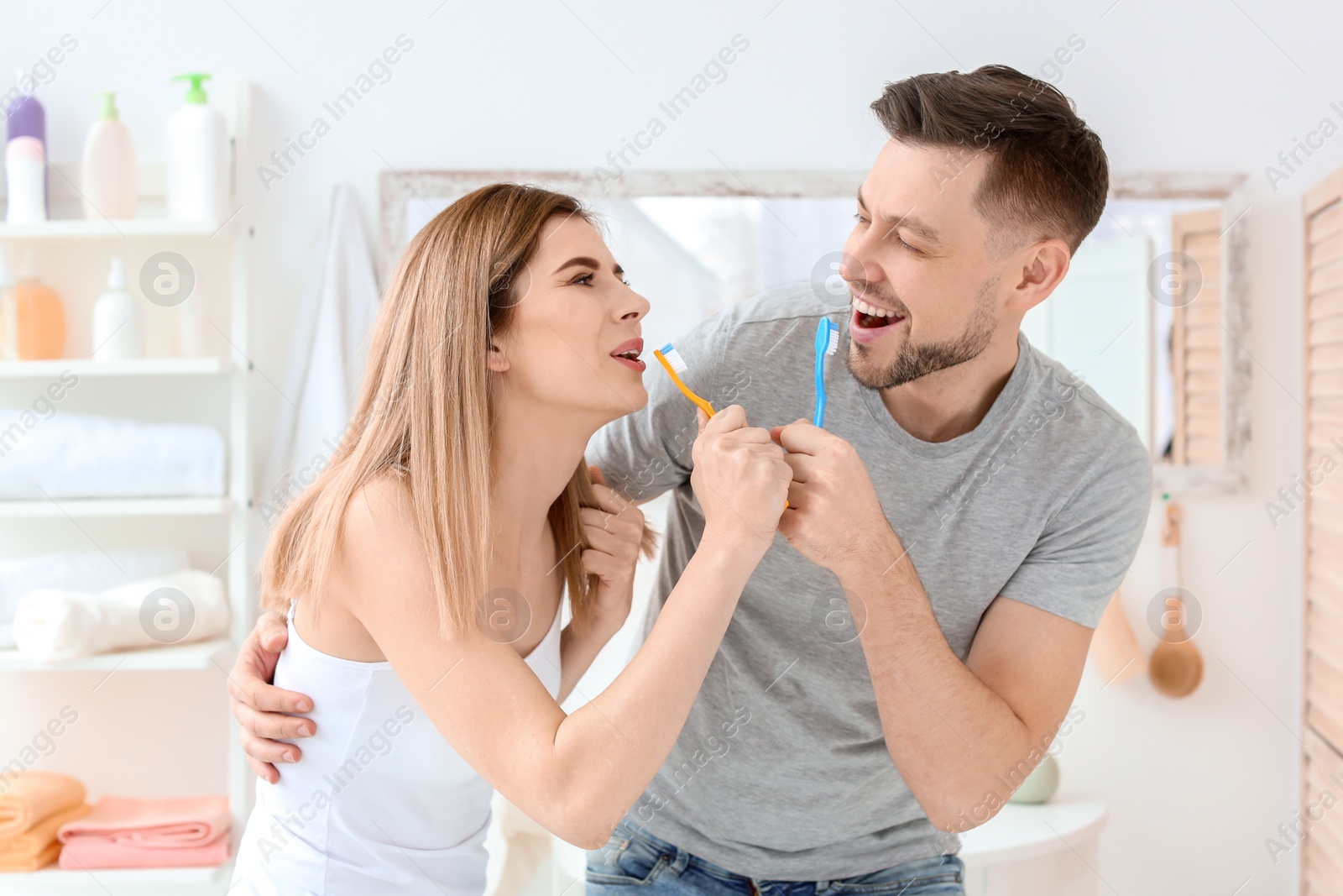 Photo of Young couple brushing teeth together in bathroom